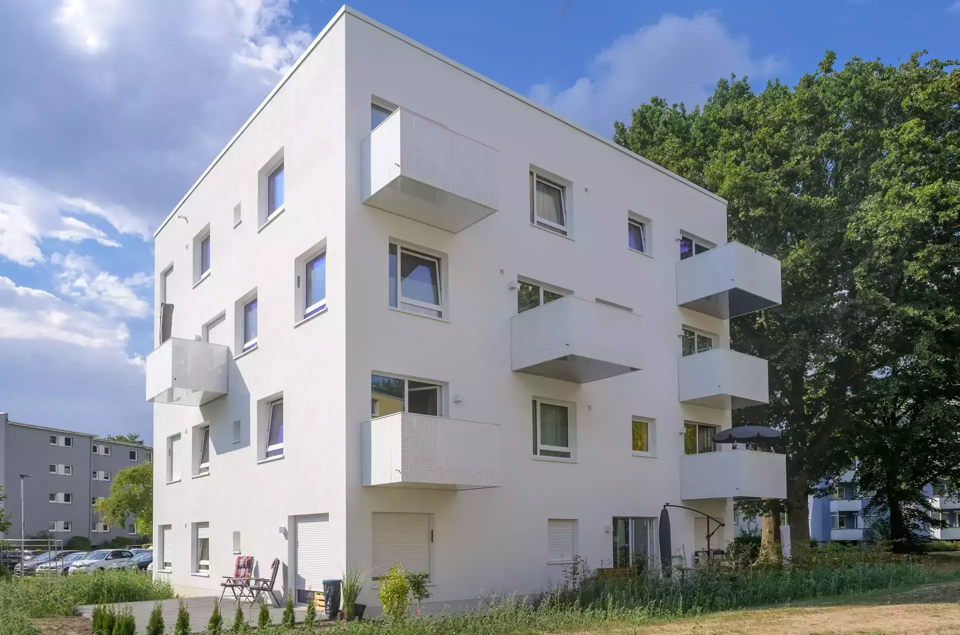 Ein moderner weisser viereckiger Wohnblock mit Balkonen