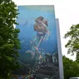 Wandbild, dass eine Meerjungfrau unter Wasser mit Fischen zeigt