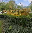 Gelber riesiger Einkaufswagen im Gebüsch