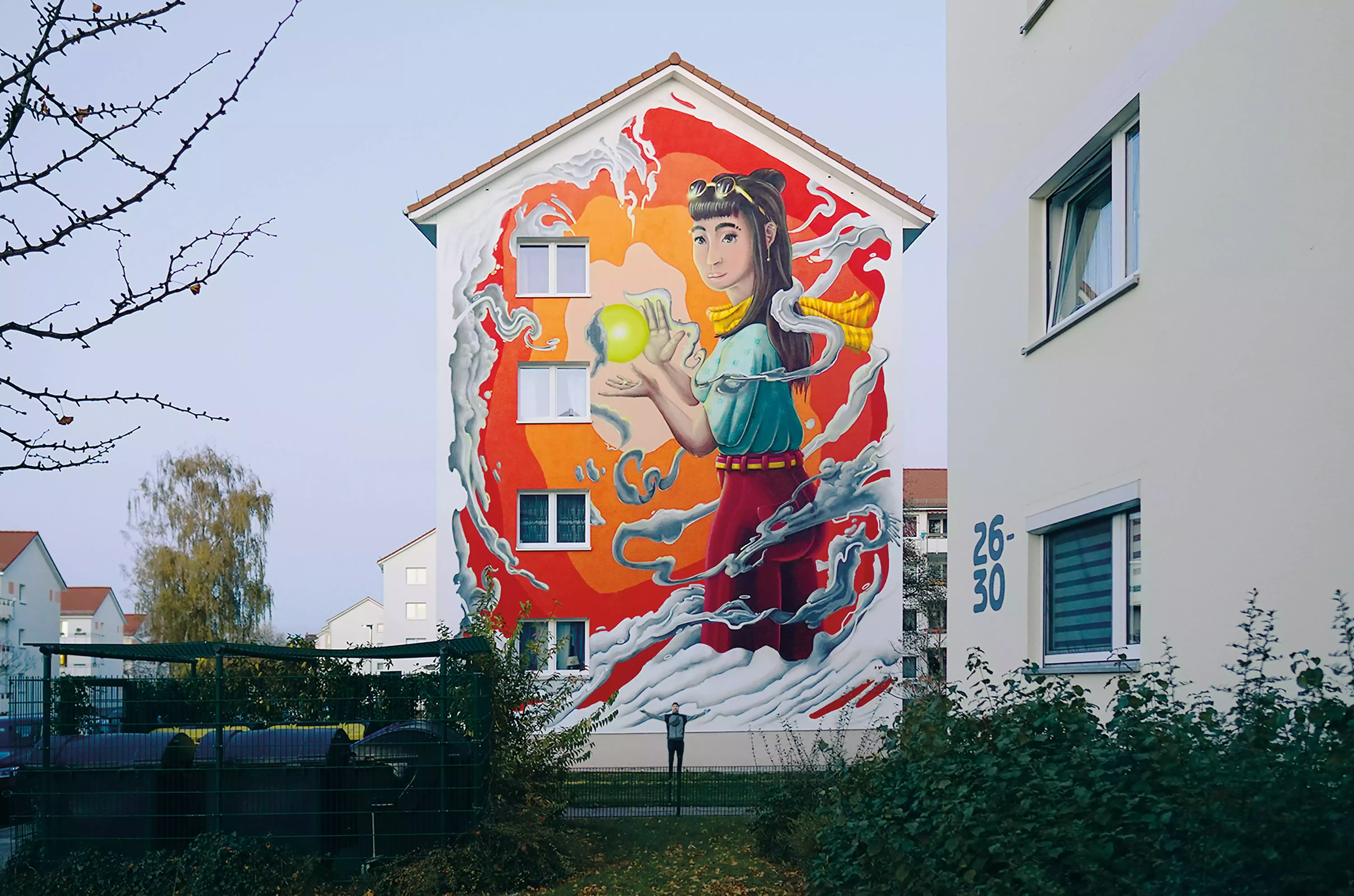 Hausfassade mit großer Malerei einer Frau mit orangenem Hintergrund