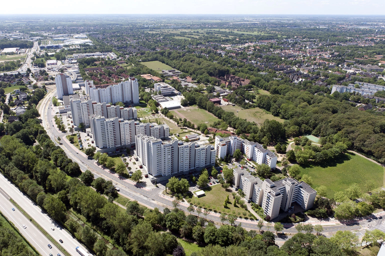 Luftblick auf eine Siedlung aus weissen Hochhaus-Wohnblöcken mit Strassen und Bäumen drumherum