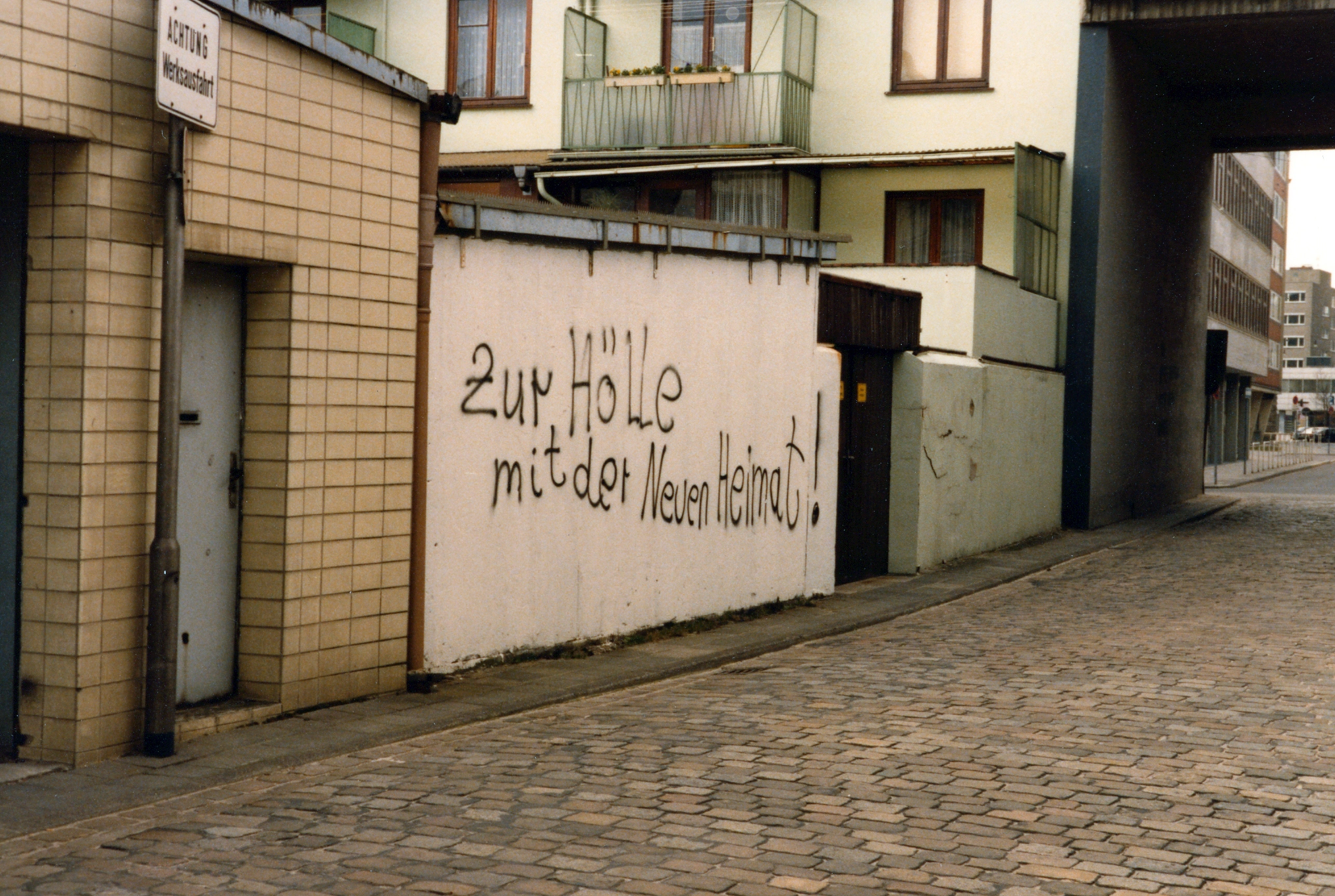 Ein Grafitti an einer Hauswand mit dem Text - zur Hölle mit der neuen Heimat