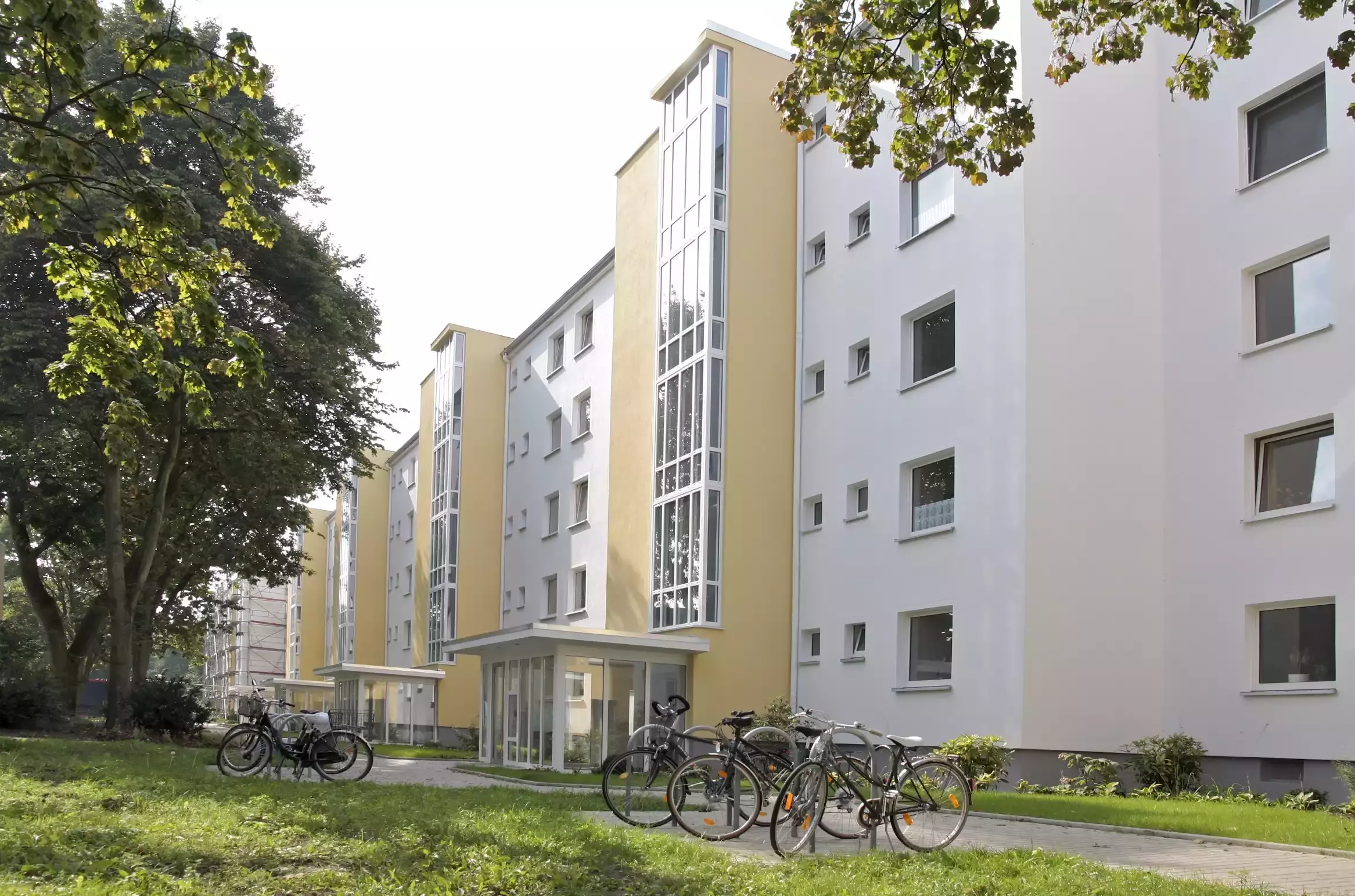Weiß-gelbes Gebäude mit Fahrradständern vor den Eingängen
