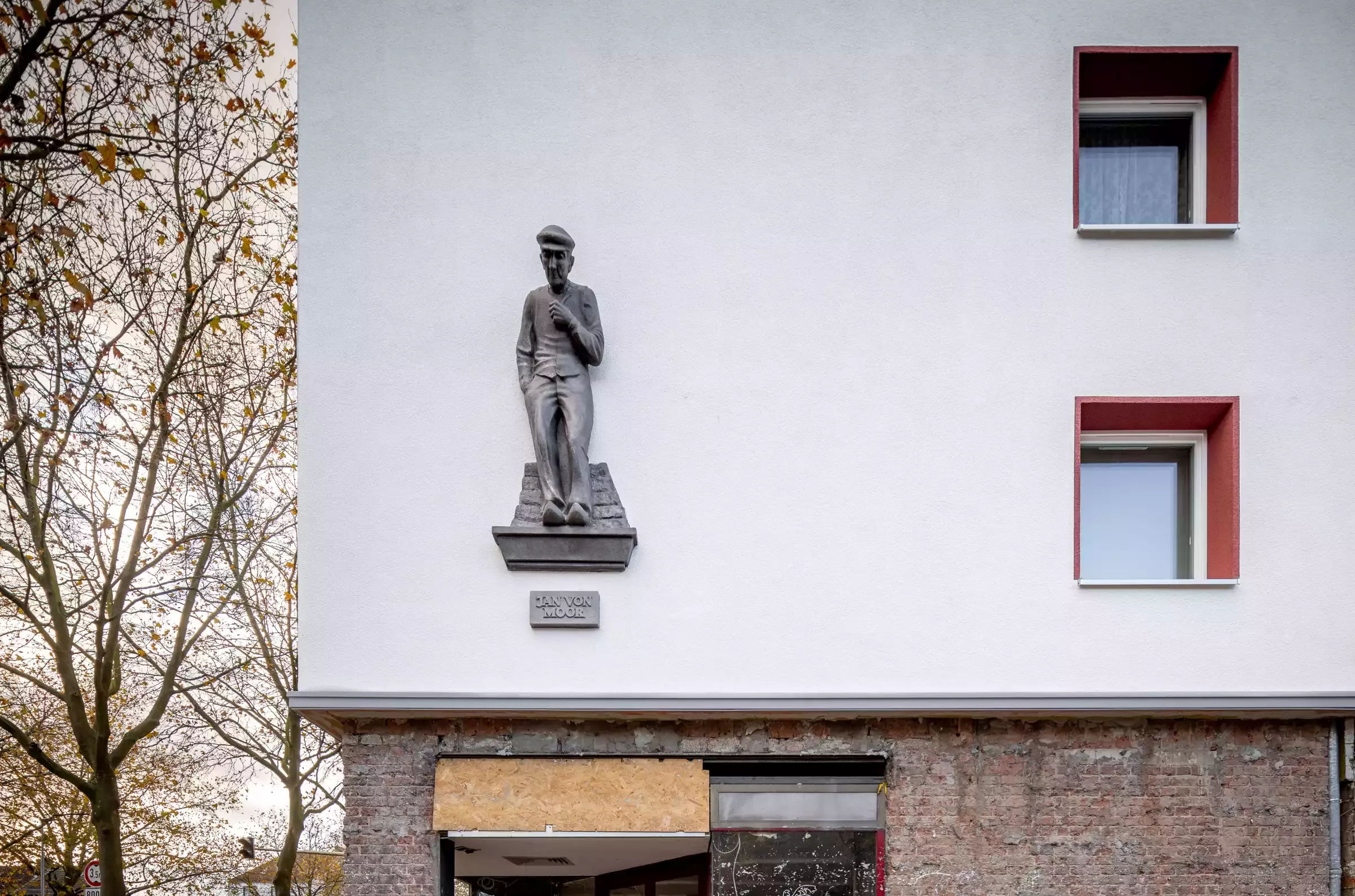 Skulptur eines herabschauenden Menschen an einer Hauswand 